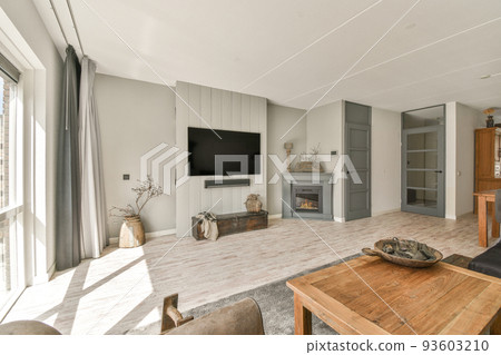 Cozy interior design of living room furnished with comfortable couch and wooden table decorated with carpet and lamp in modern attic apartment with white walls and column 93603210