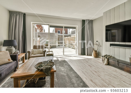 Cozy interior design of living room furnished with comfortable couch and wooden table decorated with carpet and lamp in modern attic apartment with white walls and column 93603213