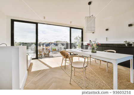 Home interior design of modern loft apartment with open kitchen in minimalist style and spacious dining zone with table and chairs Home interior design of modern loft apartment with open kitchen in minimalist style and spacious dining zone with table and chairs 93603258