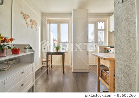 Fragment of interior of light narrow home kitchen with minimalist style white furniture with sink and stove Fragment of interior of light narrow home kitchen with minimalist style white furniture with sink and stove 93603260