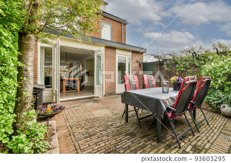 Neat paved patio with sitting area and small garden near wooden fence Neat paved patio with sitting area and small garden near wooden fence 93603295