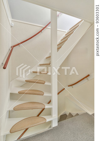 White spiral stairway connecting levels of contemporary house with wooden floor and white walls 93603301