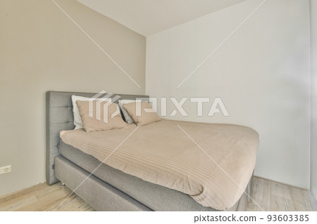 Comfortable bed covered with checkered blanket and located in light bedroom of modern apartment Comfortable bed covered with checkered blanket and located in light bedroom of modern apartment 93603385