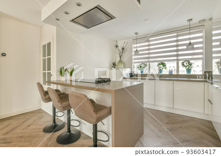Fragment of interior of light narrow home kitchen with minimalist style white furniture with sink and stove 93603417