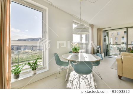 Interior of light kitchen and dining room with balcony doors in contemporary apartment at daytime 93603853
