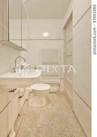 Wall hung toilet and small sink in corner in lavatory room with beige tile Wall hung toilet and small sink in corner in lavatory room with beige tile 93603860