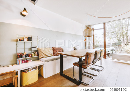 Cozy interior design of living room furnished with comfortable couch and wooden table decorated with carpet and lamp in modern attic apartment with white walls 93604192