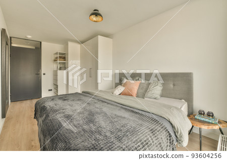 Home interior design of bedroom with bed and wooden wardrobe placed in corner near window in modern apartment Home interior design of bedroom with bed and wooden wardrobe placed in corner near window in modern apartment 93604256