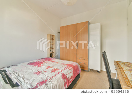 Home interior design of bedroom with bed and wooden wardrobe placed in corner near window in modern apartment Home interior design of bedroom with bed and wooden wardrobe placed in corner near window in modern apartment 93604326