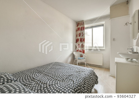 Comfortable bed and lamp placed in small narrow minimalist style bedroom with white walls and sink with mirror in modern apartment Comfortable bed and lamp placed in small narrow minimalist style bedroom with white walls and sink with mirror in modern apartment 93604327
