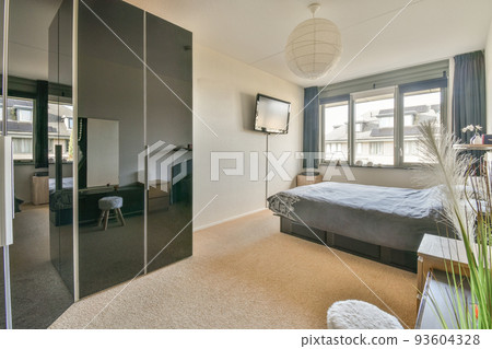 Home interior design of bedroom with bed and wooden wardrobe placed in corner near window in modern apartment Home interior design of bedroom with bed and wooden wardrobe placed in corner near window in modern apartment 93604328