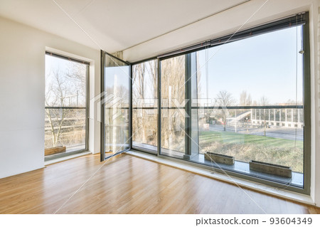 Interior of empty white room with large balcony windows with curtains and wooden parquet floor 93604349