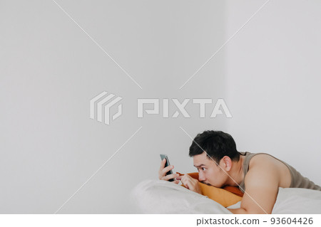 Bored and sad man using mobile phone and relaxed on beanbag sofa. Bored and sad man using mobile phone and relaxed on beanbag sofa. 93604426