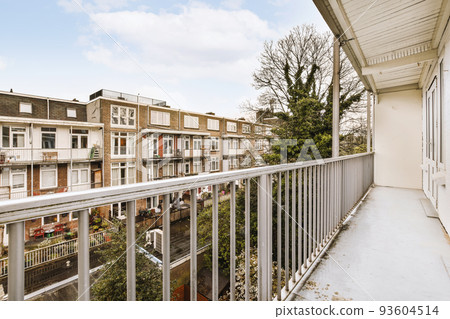 Front view of old brick buildings and cars with bicycles from small balcony with railings 93604514