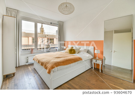 Home interior design of bedroom with bed and wooden wardrobe placed in corner near window in modern apartment 93604670