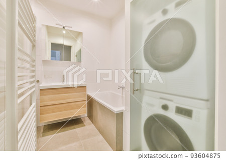 Sinks with mirrors and clean bathtub located near shower box with glass door in modern bathroom with white tiled walls Sinks with mirrors and clean bathtub located near shower box with glass door in modern bathroom with white tiled walls 93604875