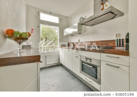 Light small home kitchen with wide window furnished with cupboards and shelves with appliances in modern urban apartment Light small home kitchen with wide window furnished with cupboards and shelves with appliances in modern urban apartment 93605199