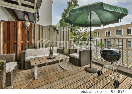 Narrow brick balcony with metal railings, wooden chair and door 93605201
