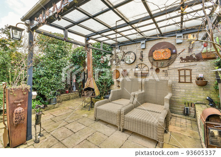 Neat paved patio with sitting area and small garden near wooden fence 93605337