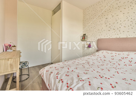 Comfortable bed with white bedclothes and bedside table with lamp placed near window and balcony door in light bedroom at home 93605462