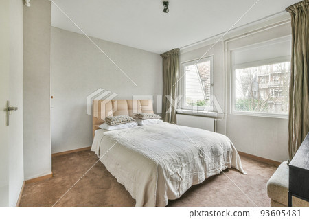 Home interior design of bedroom with bed and wooden wardrobe placed in corner near window in modern apartment Home interior design of bedroom with bed and wooden wardrobe placed in corner near window in modern apartment 93605481