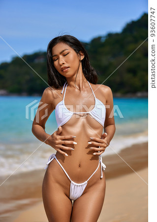 Beautiful asian girl in white bikini posing at the tropical beach 93607747