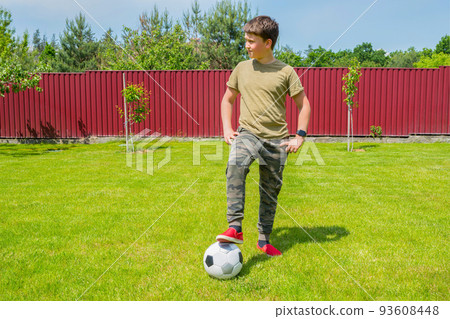 A boy with a ball in the backyard on a sunny summer day. Sport games. Healthy lifestyle concept. A boy with a ball in the backyard on a sunny summer day. Sport games. Healthy lifestyle concept. 93608448