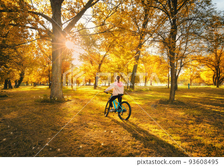 Woman riding a mountain bike and orange trees at sunset in autumn 93608495