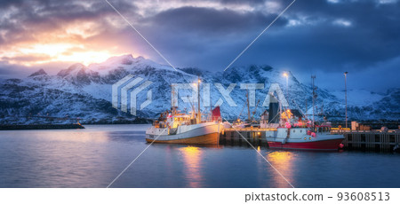 Fishing boats on the sea, snowy mountains, colorful sky 93608513