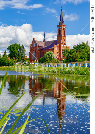 Scenic view across the lake to the Roman Catholic Church of St. Anthony in Postavy, Belarus. 93609415