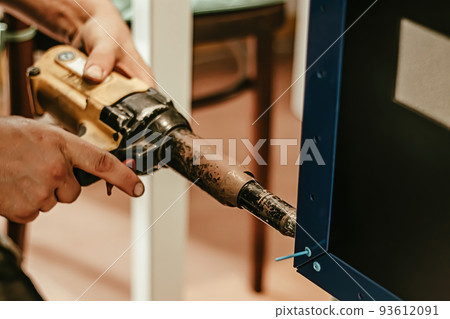 Male worker uses electric riveting gun. Hand holding riveting m 93612091