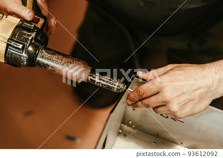 Male worker uses electric riveting gun. Hand holding riveting m 93612092