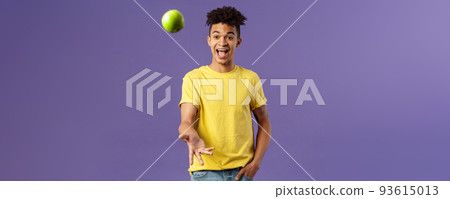 Holidays, vitamins and vacation concept. Portrait of handsome upbeat young male student asking friend something eat, catching apple and smiling happy, standing purple background 93615013