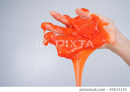 Red slime flowing down from a woman's hand on a white background. Red slime flowing down from a woman's hand on a white background. 93615135