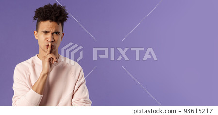 Show some respect. Portrait of angry and annoyed, displeased young hispanic man telling to keep quiet, shushing at someone being too loud, hold index finger over mouth frowning, scolding person 93615217