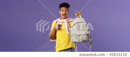 Portrait of cheerful young handsome male student, man recommending backpack, holding rucksack and show thumbs-up, bought new equipment for university semester, purple background 93615218