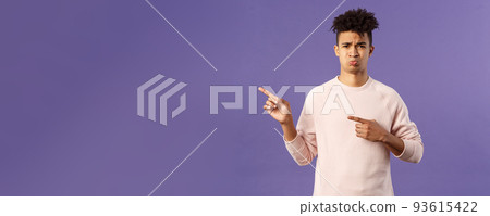 Portrait of upset and whining young cute man complaining, grimacing and sulking, pity missed chance, envy of something, pointing fingers left at awesome cool new console, cant afford it 93615422