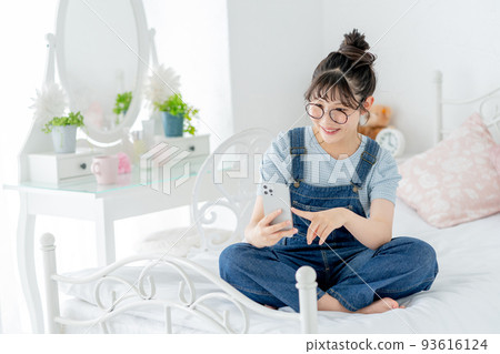 高中女生盤腿坐在床上，操作智能手機 93616124