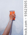 the builder grinds the wall from irregularities after applying putty 93623605