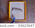 the builder dips the roller into the construction bath with paint 93623647