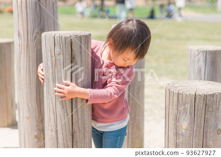 Child (girl) playing with wooden playground equipment in the park Child (girl) playing with wooden playground equipment in the park 93627927