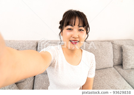 Young woman taking a selfie at home Young woman taking a selfie at home 93629838
