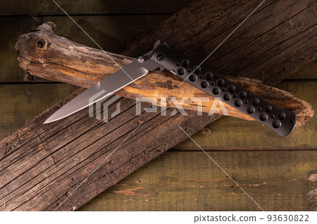 Knife in half-folded state. Knife and dry branches. Knife on old wooden sticks. View from above. Knife in half-folded state. Knife and dry branches. Knife on old wooden sticks. View from above. 93630822