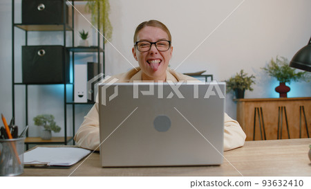 Businesswoman hiding behind laptop computer, making funny face fooling around putting his tongue out 93632410
