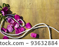 Pink rose petals and beads on a wooden background. 93632884