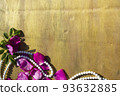 Pink rose petals and beads on a wooden background. 93632885