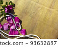 Pink rose petals and beads on a wooden background. 93632887