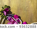 Pink rose petals and beads on a wooden background. 93632888