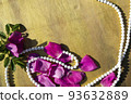 Pink rose petals and beads on a wooden background. 93632889