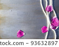 Pearl beads and rose petals on a gray wooden background close-up. 93632897